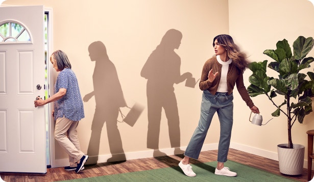 Female elderly patient with Agitation associated with dementia due to Alzheimer's disease leaves out of home in distress, away from caregiver who is watering a plant in the living room.